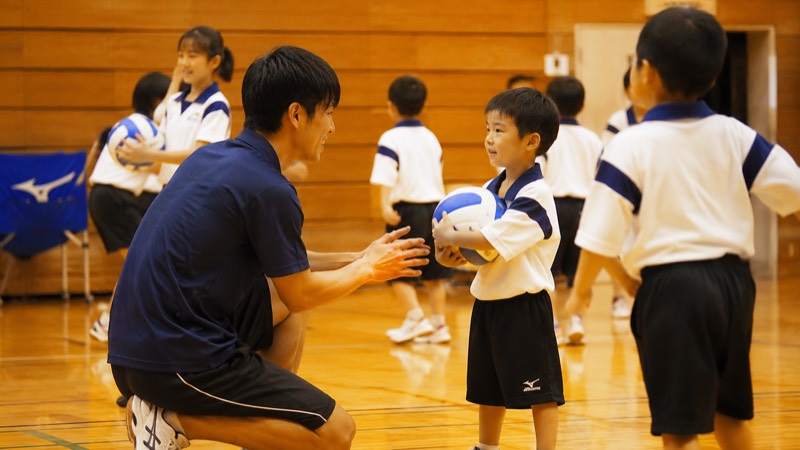 コーチが子どもに丁寧に教える様子（イメージ）