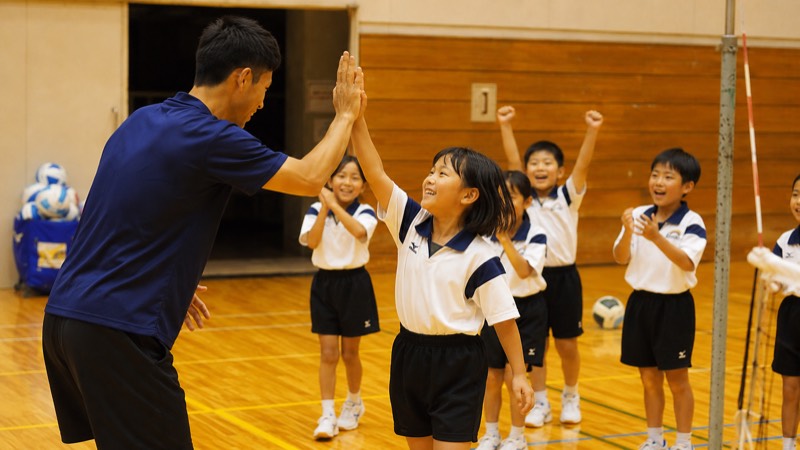 コーチと子どもがハイタッチする様子（イメージ）